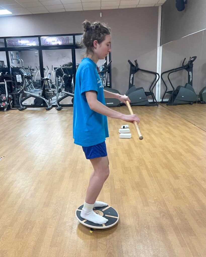 Séance de coaching sportif privé pour une femme en salle, réalisant des exercices de sport avec du matériel.