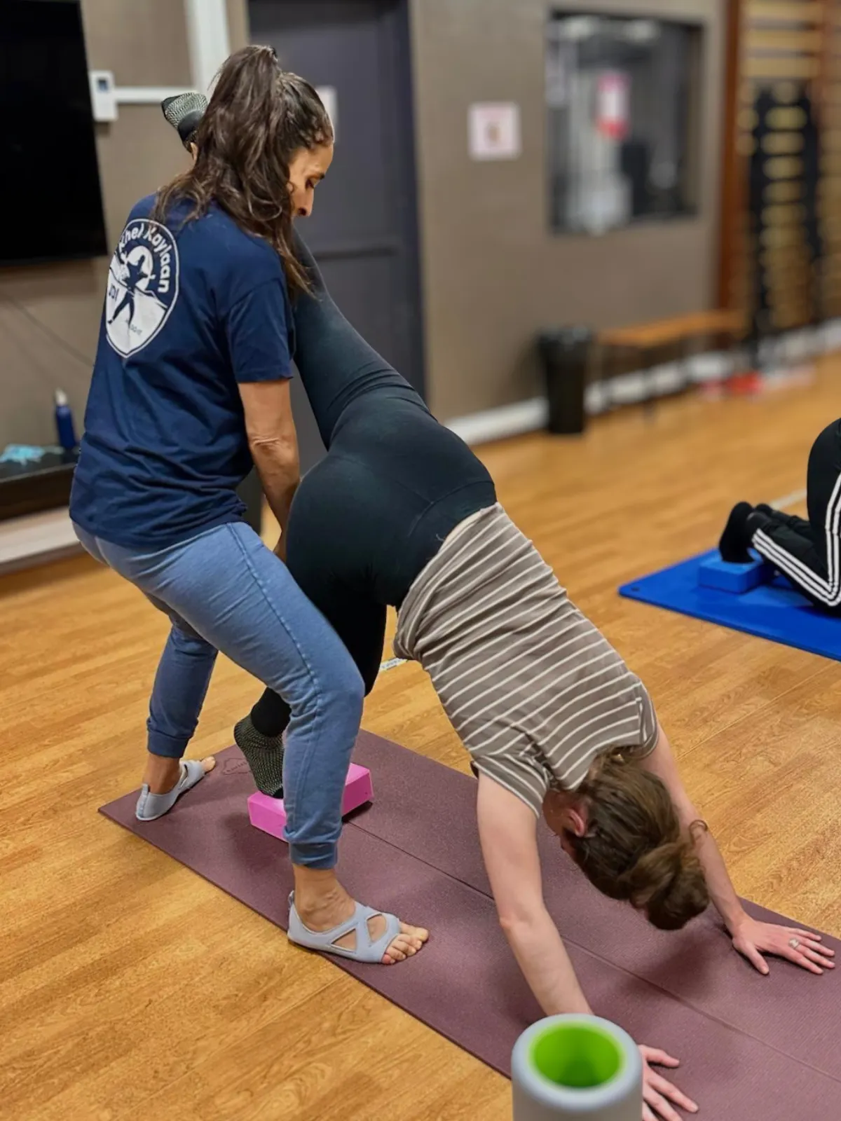 Femme en train de se faire corriger sa posture par une coach sportive lors d’un cours collectif de Pilates